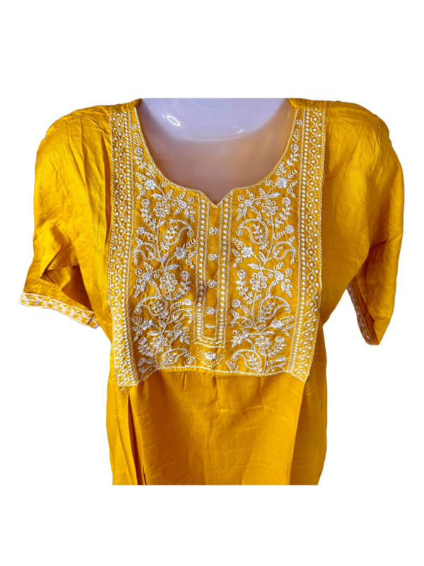 a yellow shirt with white embroidery